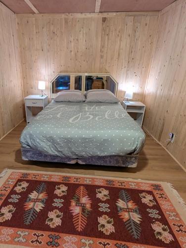 a bedroom with a bed with two tables and a rug at Chalet Lumière in Rawdon