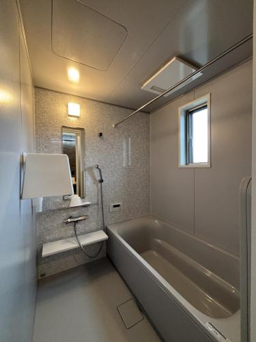 a bathroom with a large tub and a window at ハレとケ in Aso