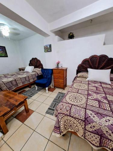 a bedroom with two beds and a wooden table and a desk at Hotel Las Palomitas in Taxco de Alarcón
