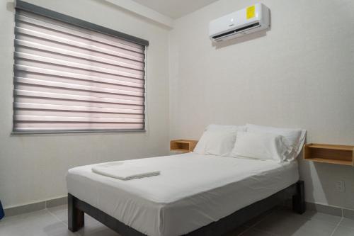 ein Schlafzimmer mit einem Bett mit weißen Laken und einem Fenster in der Unterkunft Departamento Acapulco Diamante in Acapulco