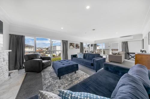 a living room with blue couches and a fireplace at Spacious house 5 minutes walk to St Helier Beach in Auckland