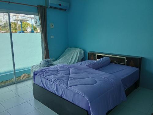 Dormitorio azul con cama y ventana grande en บ้านเพื่อนโฮมสเตย์, en Ban Muang (1)