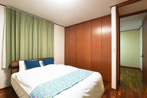 a bedroom with a large bed with blue pillows at ORENCHii in Yomitan