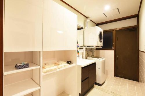 a small kitchen with white cabinets and a microwave at ORENCHii in Yomitan