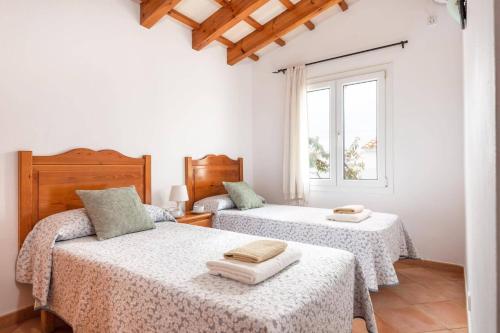 a bedroom with two beds and a window at Villa Ingrid Porter by Villa Plus in Cala'n Porter
