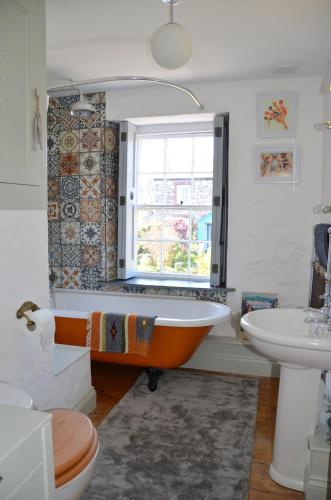 an orange tub in a bathroom with a window at Sea Haze Charlestown in St Austell