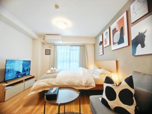 a bedroom with a bed and a tv and a couch at Sidihome 365 Apartment in Osaka