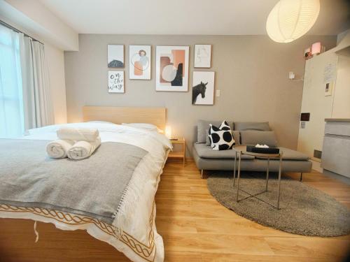 a bedroom with a bed and a couch at Sidihome 365 Apartment in Osaka