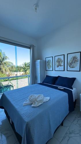 1 dormitorio con 1 cama azul y 2 toallas blancas en pousada tudo a ver, en Salinas da Margarida