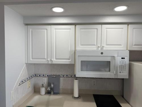 Una cocina con gabinetes blancos y un microondas. en New Amazing Ocean View Beachfront Entire Apartment Direct access to Beach, en Daytona Beach