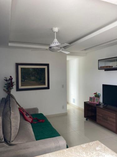a living room with a couch and a ceiling fan at NoiZ Apartment - SofaHouse in Rio das Ostras