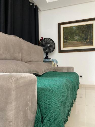 a couch sitting in a living room with a green blanket at NoiZ Apartment - SofaHouse in Rio das Ostras