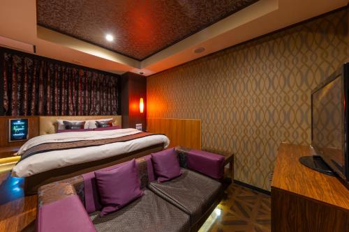 a bedroom with a bed with purple pillows at ホテルクリスタルゲート木更津 in Kisarazu