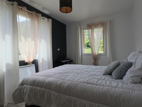 1 Schlafzimmer mit einem weißen Bett und 2 Fenstern in der Unterkunft L'R du Roc : Appartement Duplex 4* avec Terrasse et Garage - FR-1-858-7 in La Bourboule