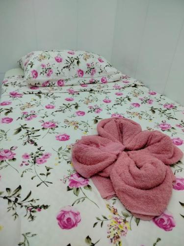 a bed with a pink towel on it with flowers at Quarto para solteiro perto do aeroporto e parques in Belém