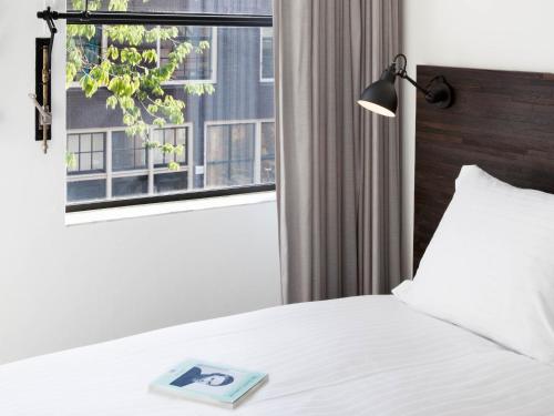 a bedroom with a bed and a window with a book on it at Stout & Co. in Amsterdam