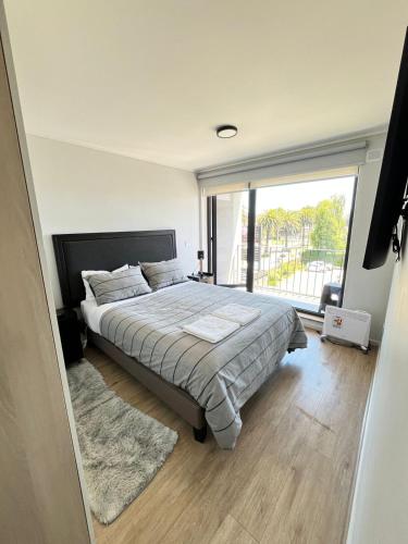 a bedroom with a large bed and a large window at Departamento céntrico nuevo in Valdivia