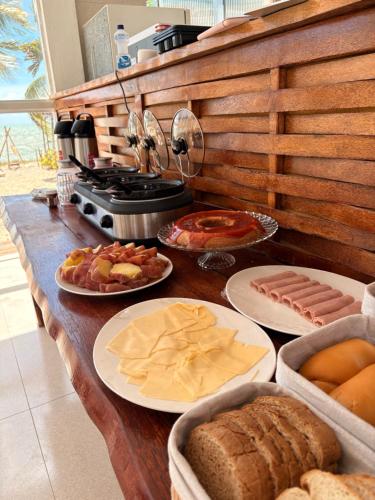 a table with plates of bread and other food on it at Pousada Amarílis in Barra de Santo Antônio