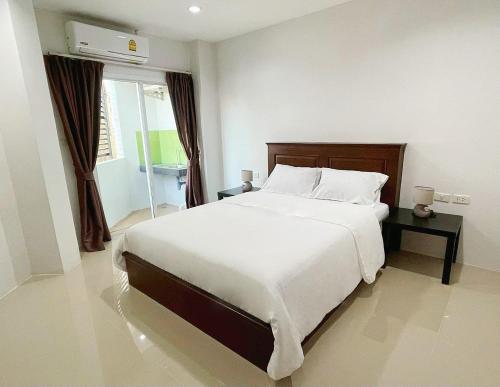 a bedroom with a large white bed and a window at The Nap House Phuket Town in Phuket