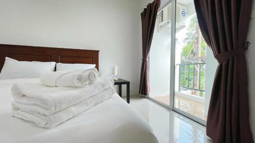 a bedroom with white towels on a bed with a window at The Nap House Phuket Town in Phuket Town