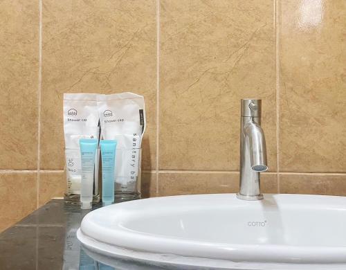 a sink with two toothbrushes and two cups on a counter at The Nap House Phuket Town in Phuket Town