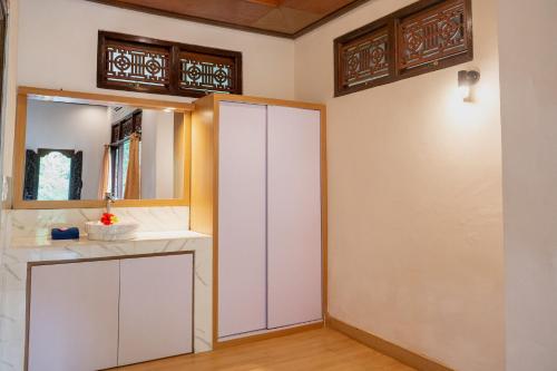 a bathroom with a white cabinet and a mirror at Nick's Pension in Ubud