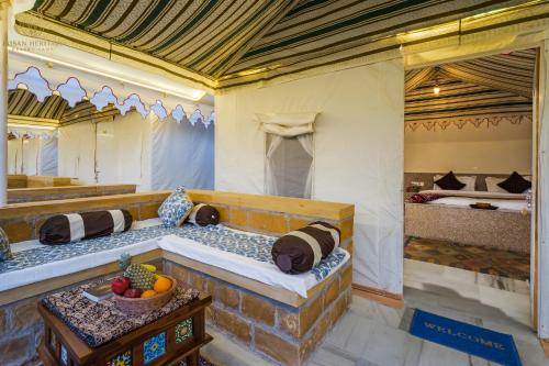 a room with two beds and a bowl of fruit on a table at Jaisan Heritage Desert Camp in Jaisalmer