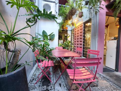 a red table and chairs in a patio with plants at The Brownstone Hostel & Space in Ipoh