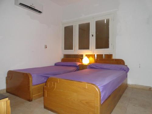 two beds in a room with purple sheets at Villa at Karawan Resort in Al Ḩammām