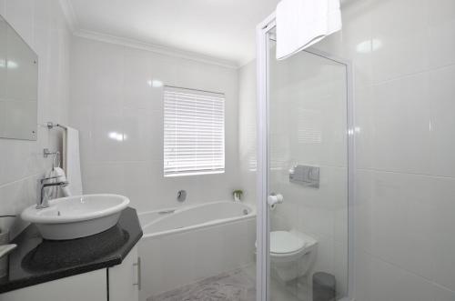 a white bathroom with a sink and a toilet at sandytoesatbigbay in Cape Town