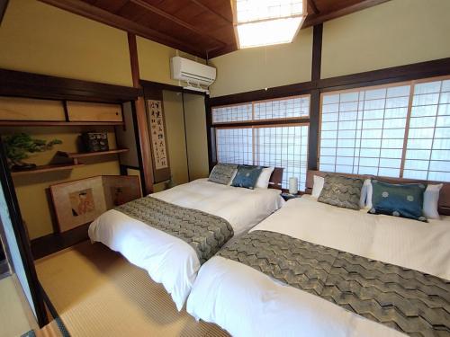 - 2 lits dans une chambre avec fenêtres dans l'établissement さぬきの宿 古民家 岡本, à Oda