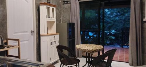 a kitchen with black chairs and a table and a window at Baan Ya-Nhom in Ko Sukon
