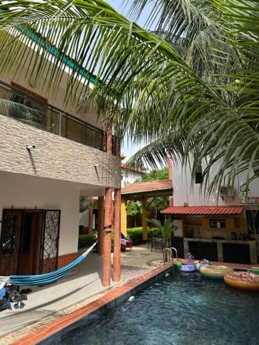une piscine en face d'une maison avec un palmier dans l'établissement Tekrour- la case des hotes - Chambre individuelle avec piscine et terrasse, à Mbour