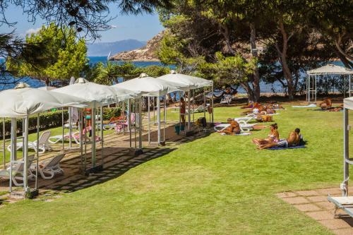 people sitting on the grass in a park with umbrellas at Hotel Calamosca in Cagliari