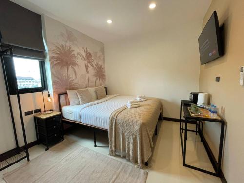 a bedroom with a bed and a tv on the wall at Mitsu Guesthouse, Karon Beach in Karon Beach