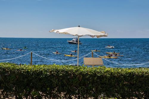 a beach with an umbrella and people in the water at Hotel Calamosca in Cagliari