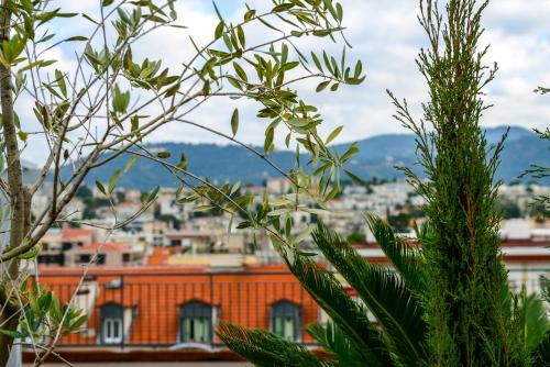 a view of a city from behind a tree at Hôtel & Appartements Monsigny in Nice