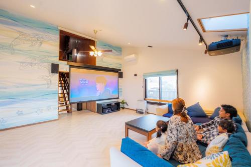 a group of people sitting in a living room watching tv at まるで映画館 本格シアター 寝室6部屋 大家族大集合 海まで徒歩すぐ ---オーシャニア一宮--- in Ichinomiya