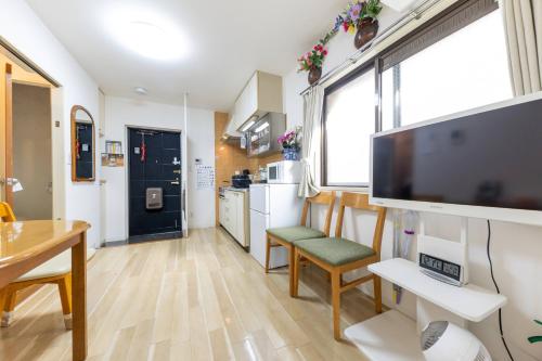 a living room with a large tv and a kitchen at Akazu-hostel new-ST0112 in Naka-tomi