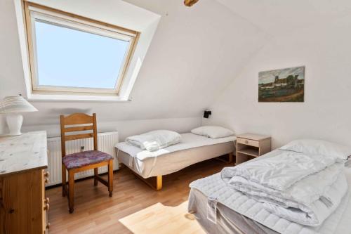 two beds in a room with a window and a chair at Holiday Apartment With Sea View, Near The Beach in Lebøl