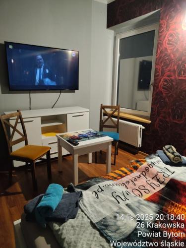 a living room with a flat screen tv and a table at TRZY SOWY prywatne pokoje 24h wygodnelokumpl in Bytom