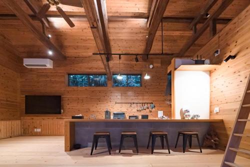 a large room with a bar with stools at 山小屋吉丁 in Ukiha