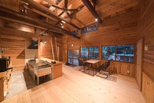 Una cocina abierta y un comedor de una cabaña de troncos en 山小屋吉丁, en Ukiha