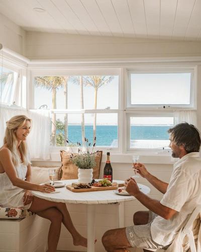 a man and woman sitting at a table with wine glasses at George @ Ethel & Odes in Bundeena