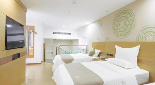 a bedroom with two beds and a flat screen tv at GreenTree Inn Zhangjiagang Yangshe Old Street Stadium in Zhangjiagang