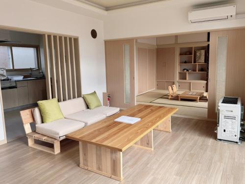 a living room with a couch and a wooden table at ''内装フルリフォーム'' HOKKAIDO l 千歳空港まで30分 l 一棟貸し8名迄OK l 白樺 Shirakaba in Yuni