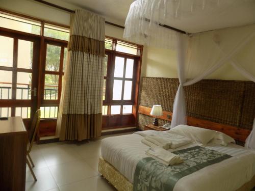 a bedroom with a bed in a room with windows at Kalya Courts Hotel Fort Portal in Fort Portal
