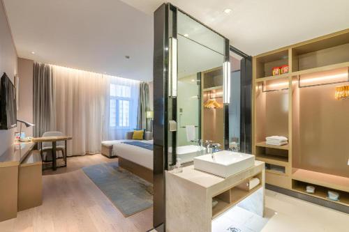 a bathroom with a sink and a bed and a mirror at Echarm Hotel Jinan Railway Station Daming Lake in Jinan