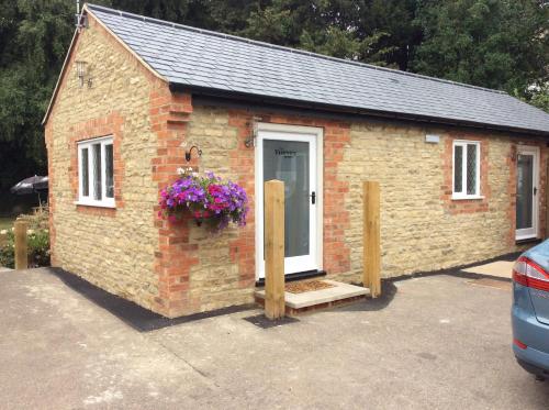 a small brick house with a door and flowers at Three-Cranes in Turvey