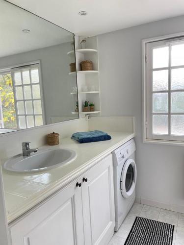 a white bathroom with a sink and a washing machine at Charmant Mazet en campagne provencale in Châteaurenard